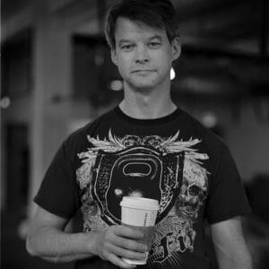 black and white photo of a white man holding a takeaway coffee cup