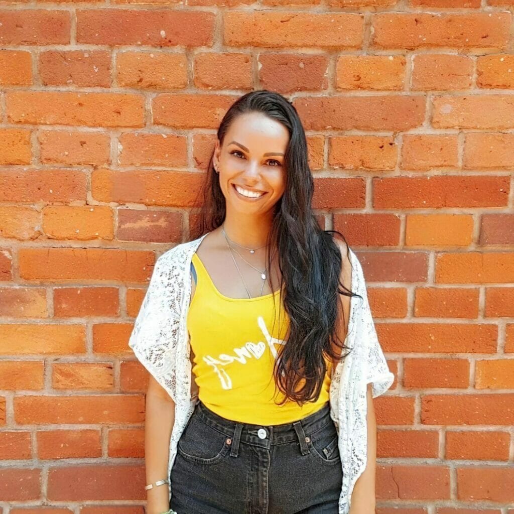 jessika-lagarde-headshot-photo-of-brazilian-woman-smiling-in-front-of-brick-wall